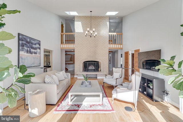 living area featuring wood finished floors, a skylight, a fireplace, and a chandelier