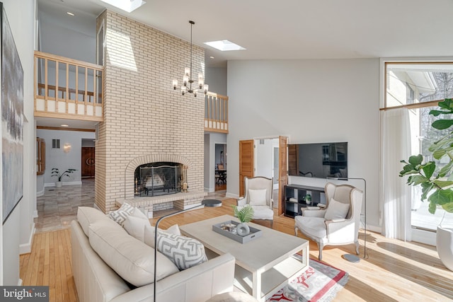 living area with a brick fireplace, baseboards, a high ceiling, an inviting chandelier, and wood finished floors