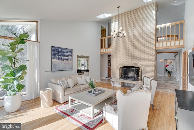 living area featuring baseboards, a fireplace, a towering ceiling, wood finished floors, and a notable chandelier