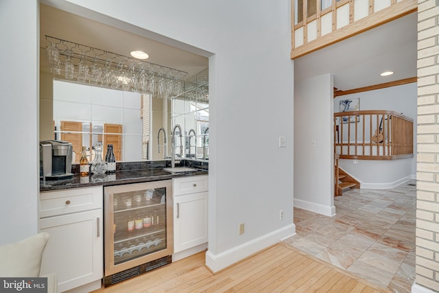 bar featuring beverage cooler, a sink, stairway, baseboards, and wet bar