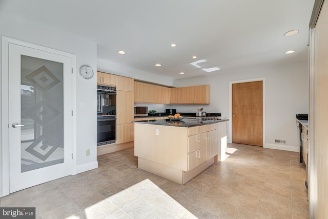 kitchen featuring visible vents, light brown cabinetry, dobule oven black, dark countertops, and a center island