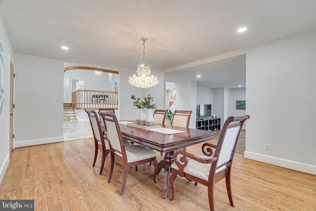 dining room with arched walkways, recessed lighting, baseboards, and light wood-style floors