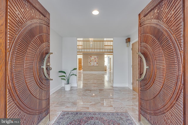 corridor with baseboards and marble finish floor