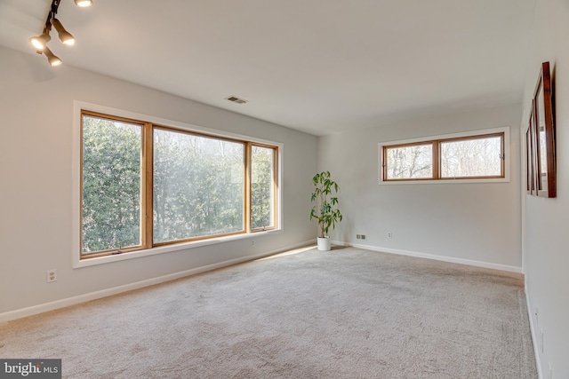 carpeted empty room with plenty of natural light, visible vents, and baseboards