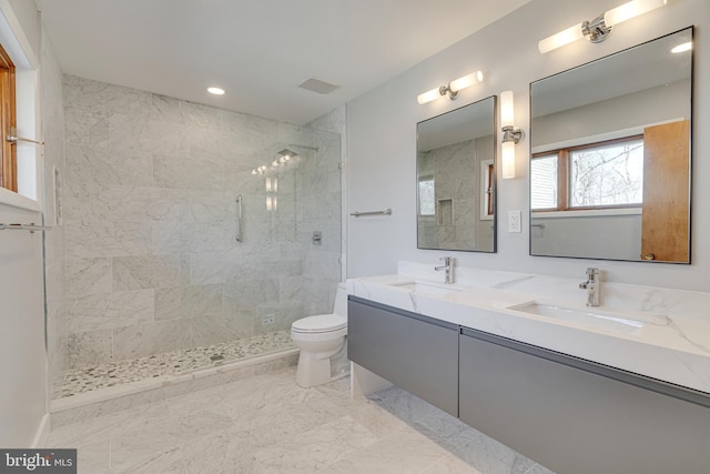 bathroom featuring toilet, a tile shower, and a sink