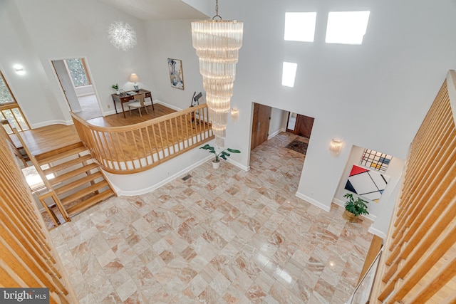 entryway with an inviting chandelier, stairway, baseboards, and a towering ceiling