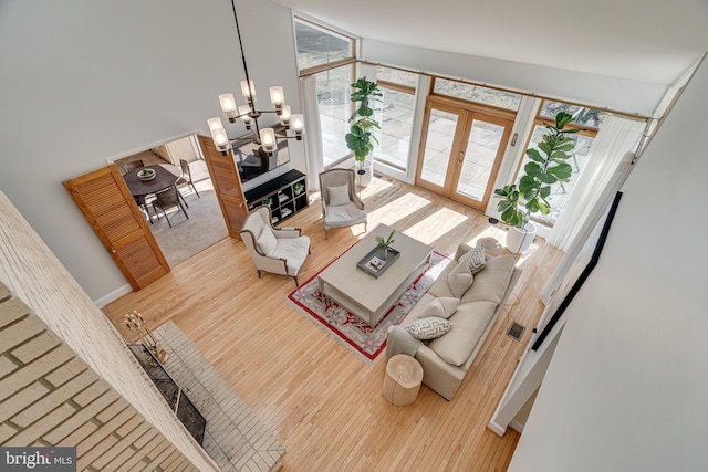 living room featuring wood finished floors, baseboards, an inviting chandelier, french doors, and expansive windows