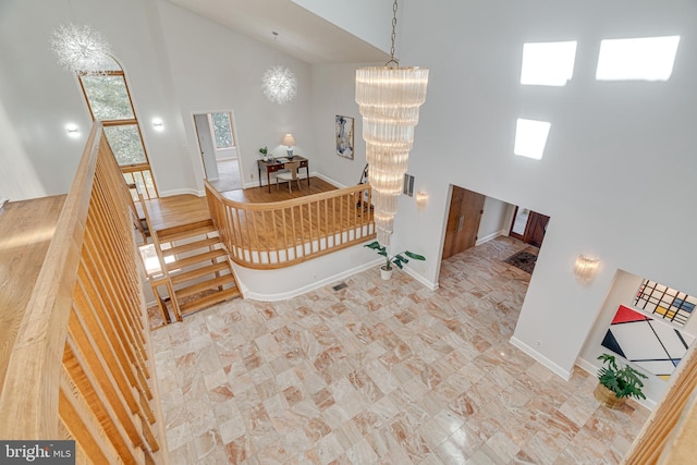 stairway with baseboards, visible vents, high vaulted ceiling, and an inviting chandelier