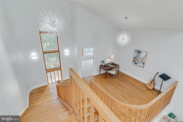 interior space featuring an inviting chandelier, wood finished floors, baseboards, and high vaulted ceiling