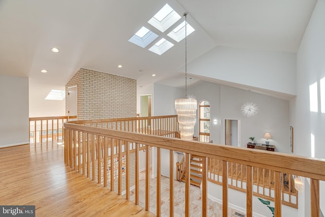 hall featuring an inviting chandelier, a skylight, recessed lighting, and wood finished floors