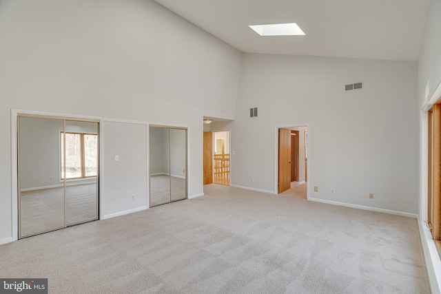 unfurnished bedroom with visible vents, light colored carpet, baseboards, and multiple closets