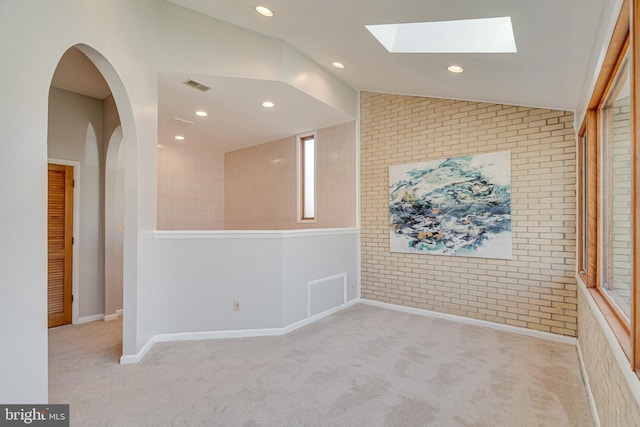 spare room with visible vents, brick wall, recessed lighting, vaulted ceiling, and carpet flooring