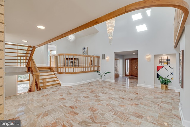 unfurnished living room featuring beam ceiling, stairway, a high ceiling, an inviting chandelier, and baseboards