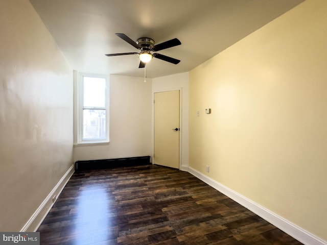 unfurnished room featuring baseboards, dark wood finished floors, and a ceiling fan