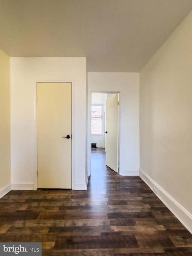 empty room featuring baseboards and dark wood-style flooring