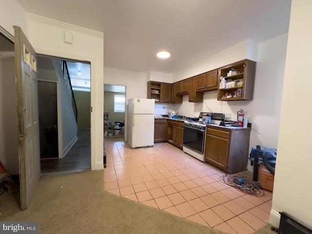 kitchen with gas range, light colored carpet, freestanding refrigerator, light tile patterned flooring, and open shelves