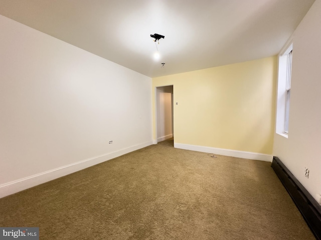 unfurnished room featuring a baseboard radiator, baseboards, and carpet