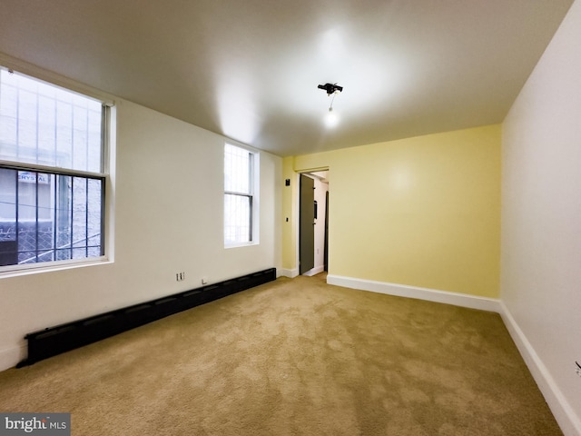 spare room featuring baseboards, baseboard heating, and carpet flooring