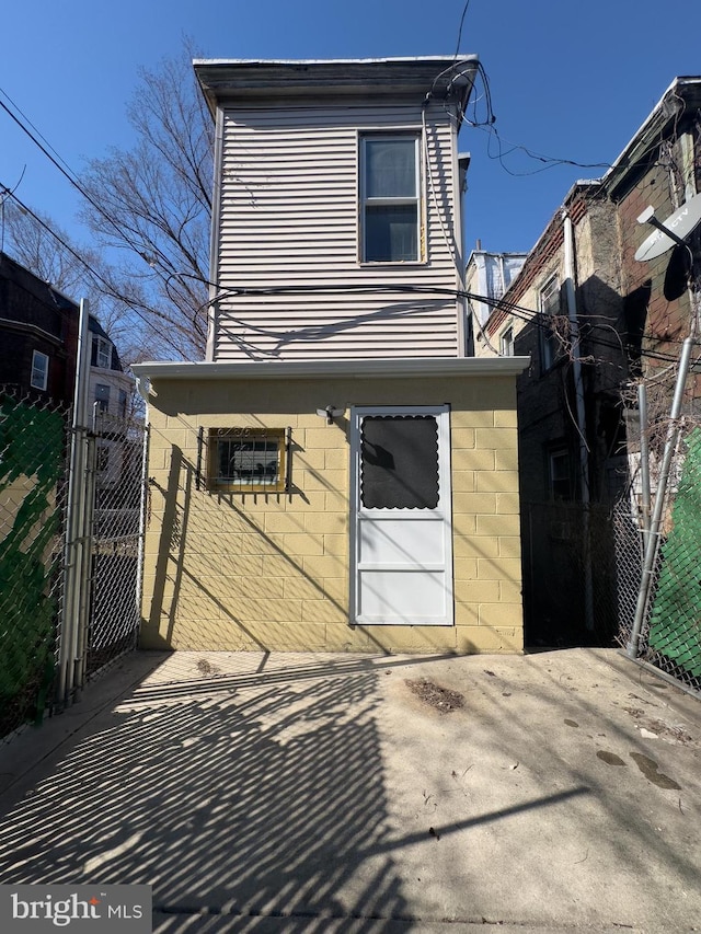 view of front facade with a gate, concrete block siding, and fence