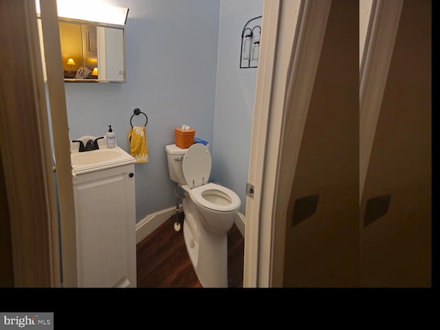 bathroom featuring toilet, vanity, baseboards, and wood finished floors