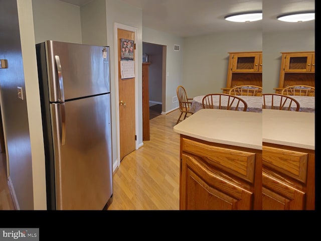 kitchen featuring light wood finished floors, brown cabinets, light countertops, and freestanding refrigerator