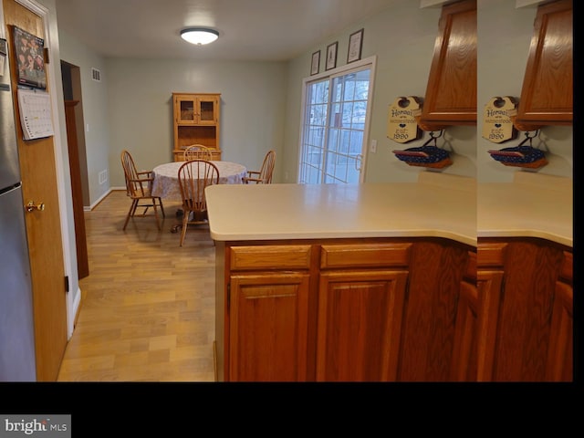 kitchen with visible vents, light wood-type flooring, brown cabinets, a peninsula, and light countertops