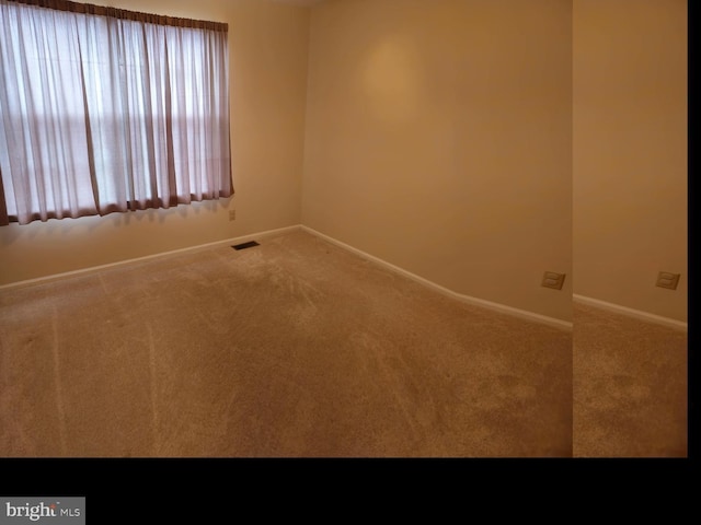 unfurnished room with visible vents, baseboards, and carpet floors