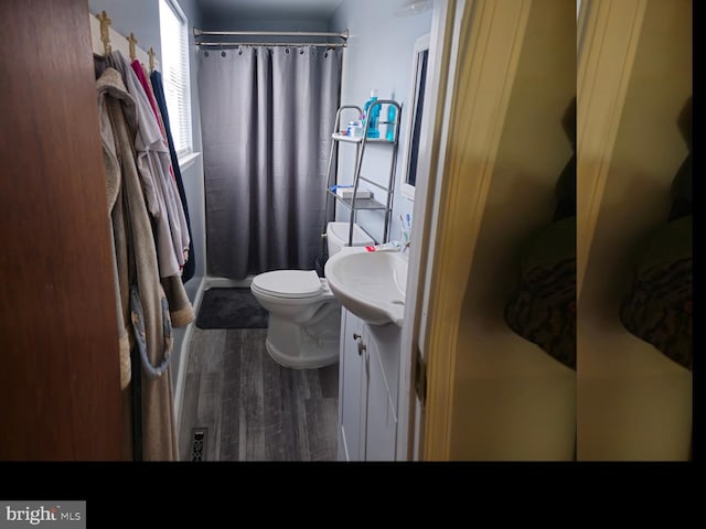 full bathroom featuring curtained shower, toilet, vanity, and wood finished floors