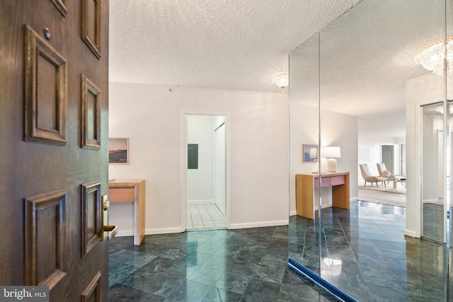 bathroom featuring electric panel, baseboards, a textured ceiling, and a chandelier