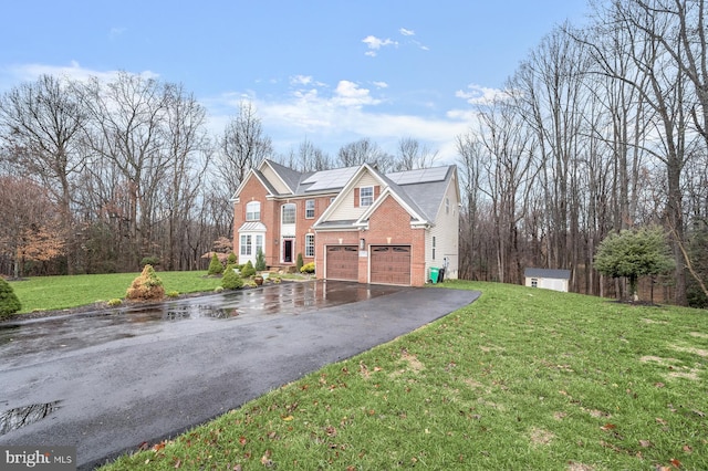 view of front of property with aphalt driveway, brick siding, solar panels, and a front lawn