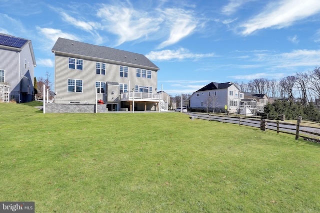 rear view of property with stairs, a deck, a yard, and fence