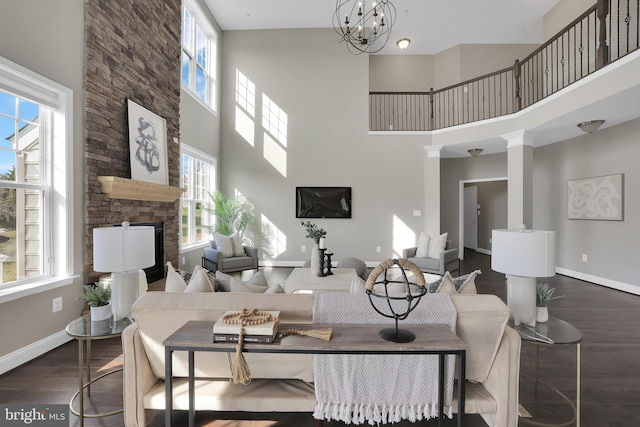 living area with a wealth of natural light, baseboards, a stone fireplace, and wood finished floors