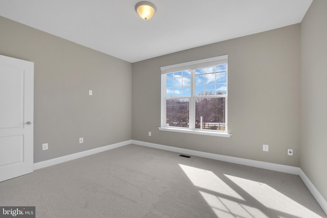 carpeted spare room featuring visible vents and baseboards