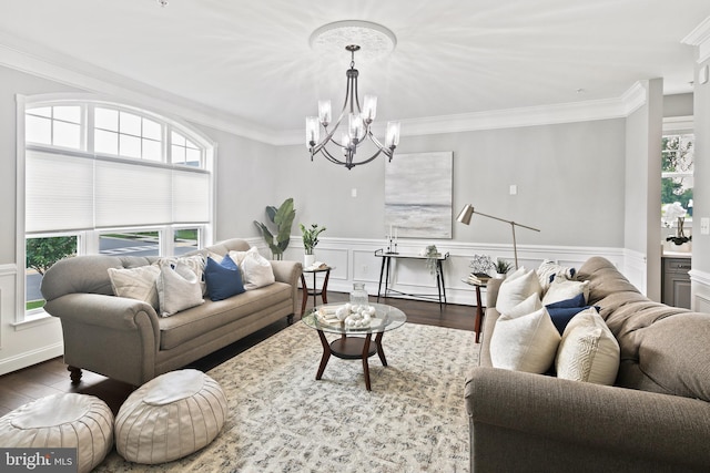 living area featuring a notable chandelier, a wainscoted wall, crown molding, and wood finished floors