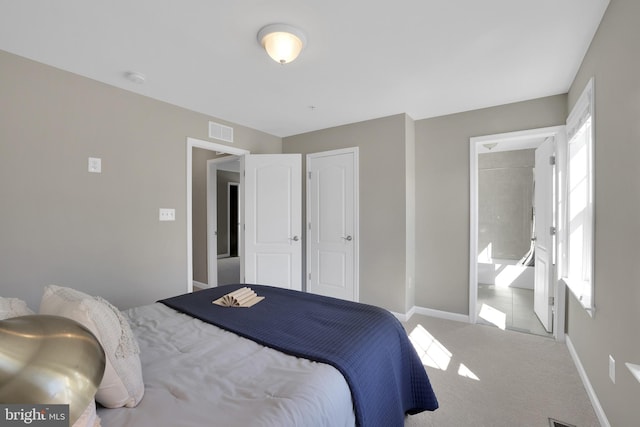 carpeted bedroom with visible vents, baseboards, and ensuite bath