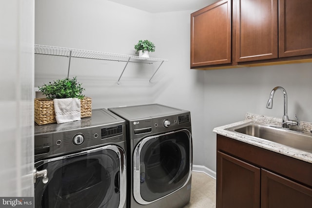 laundry room with washing machine and clothes dryer, cabinet space, baseboards, and a sink