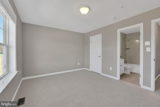 unfurnished bedroom featuring carpet flooring, baseboards, visible vents, and ensuite bathroom