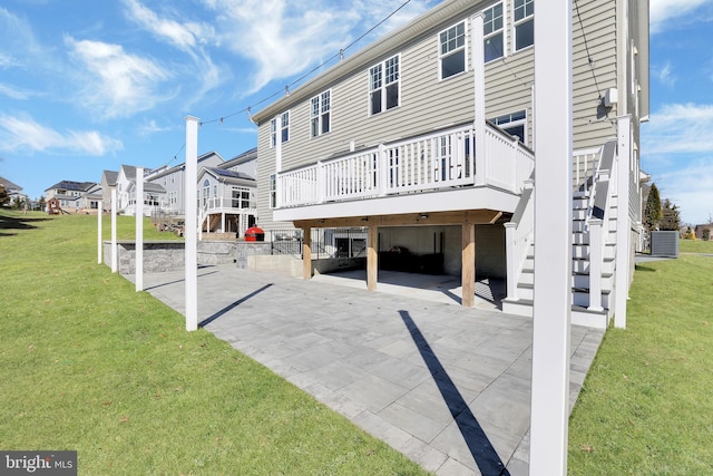 rear view of property featuring a residential view, stairs, central AC, a lawn, and a deck