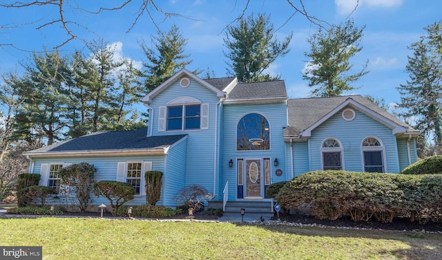 traditional-style house with roof with shingles and a front yard