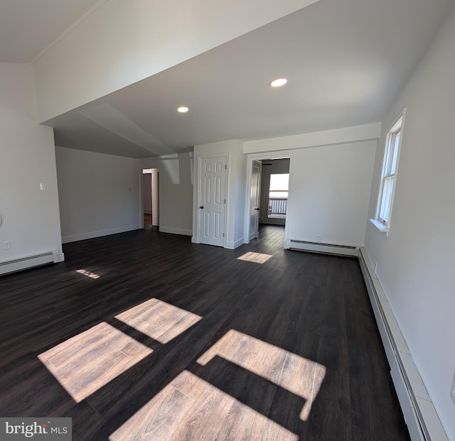 unfurnished living room featuring a baseboard heating unit, dark wood finished floors, and baseboards