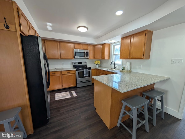 kitchen with dark wood-style floors, appliances with stainless steel finishes, baseboards, and a peninsula