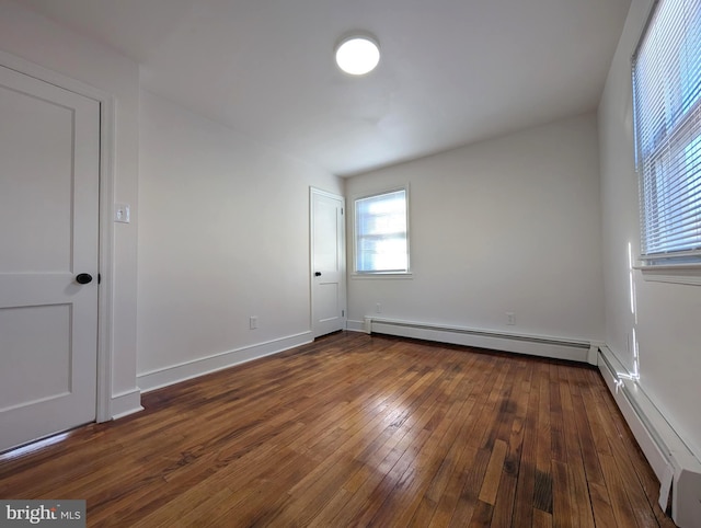 empty room with dark wood finished floors, baseboards, and baseboard heating