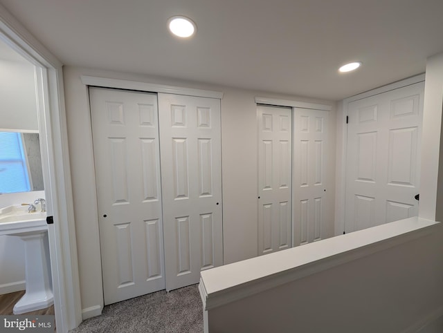 hallway featuring recessed lighting, dark carpet, and baseboards