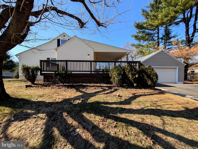 exterior space featuring concrete driveway, a wooden deck, and a front yard