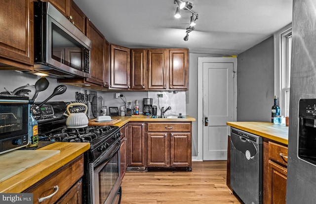 kitchen with butcher block countertops, light wood-style flooring, appliances with stainless steel finishes, and a sink