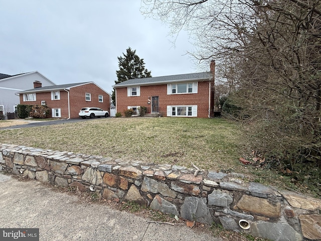 view of front of property with a front yard, brick siding, and a chimney