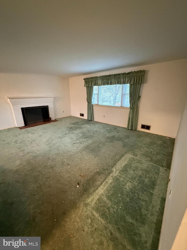 unfurnished living room featuring visible vents, carpet flooring, and a fireplace