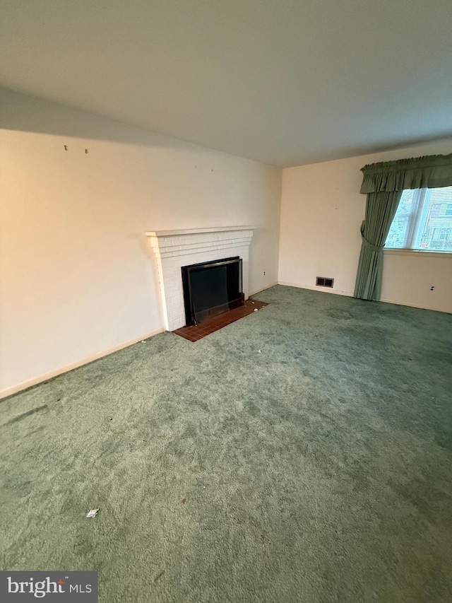 unfurnished living room featuring carpet flooring, a fireplace with flush hearth, and visible vents