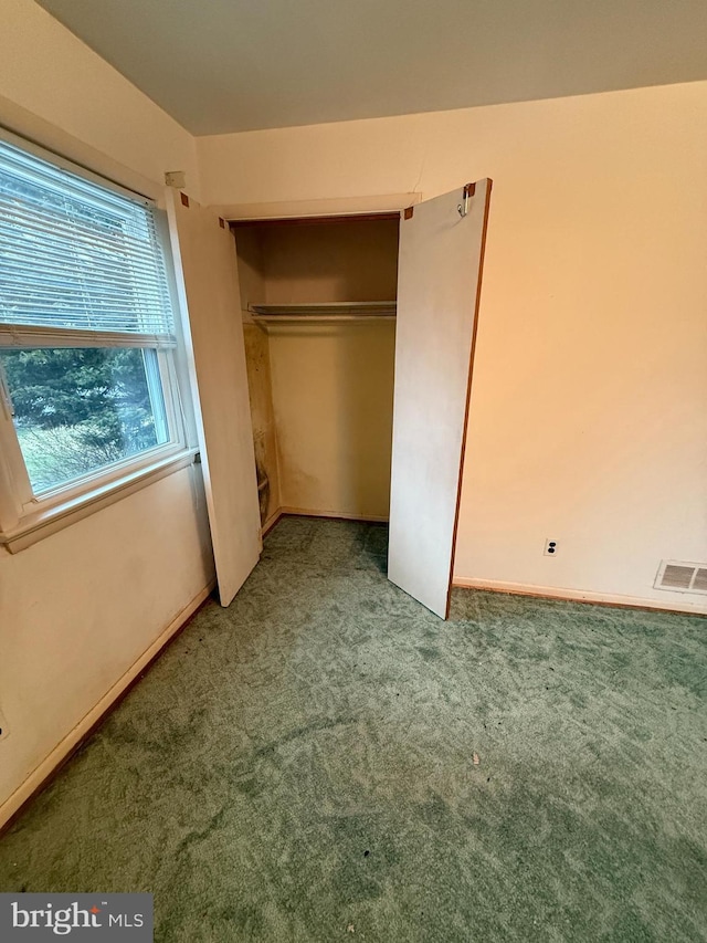 unfurnished bedroom featuring carpet, visible vents, and a closet