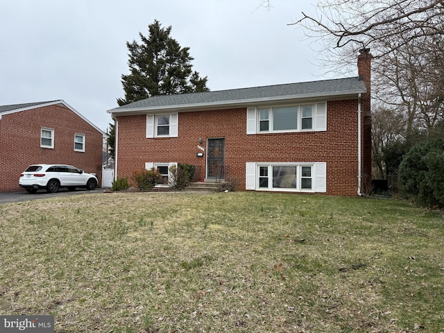 rear view of house with brick siding, a lawn, and a chimney